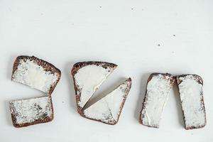 Sliced of brown bread with butter on a white wooden background. Top view. Copy, empty space for text photo