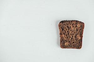 Slic of fresh brown bread with raisins on a white wooden background photo