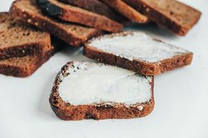 Sliced of brown bread with butter on a white wooden background. Top view. Copy, empty space for text photo