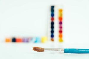 pinturas gouache de colores y pincel para pintar sobre una mesa de madera blanca foto