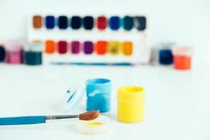 Colorful gouache paints and brush for painting on white wooden table photo