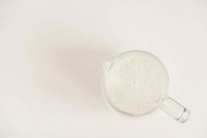 Glass jug with milk on a white table photo