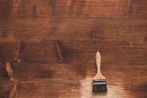 Brush with wooden handle and natural bristles against the background of painted brown wooden planks photo