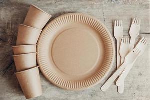 Wooden forks and paper cups with plates on wooden background photo