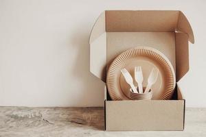 Wooden forks and paper cups with plates on box paper background photo