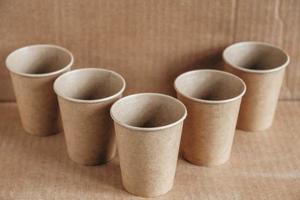 Disposable paper cups on kraft paper background. Eco friendly disposable tableware. Zero waste concept. Copy, empty space for text photo