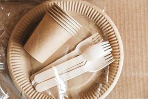 Wooden forks and paper cups with plates on kraft paper background photo