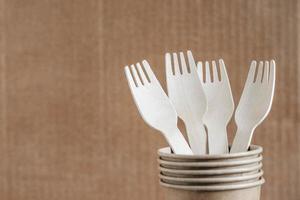 Wooden forks and paper cups on kraft paper background photo