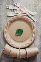 tenedores de madera y vasos de papel con platos sobre fondo de madera foto