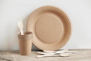 tenedores de madera y vasos de papel con platos sobre fondo de madera foto