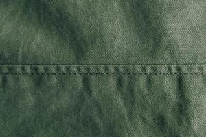 Green denim background decorated with a seam. Green denim seam texture photo