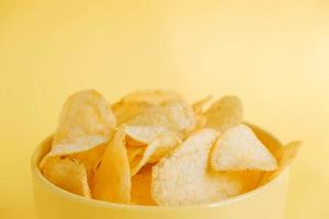 Potato chips in a yellow bowl on a yellow background photo