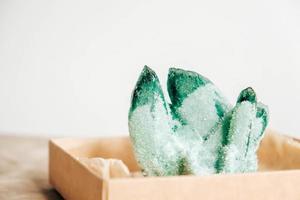 Raw emerald and gemstone rough rock crystal in a kraft paper box on wooden background