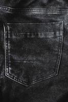 Fragment of black denim trousers with a back pocket photo