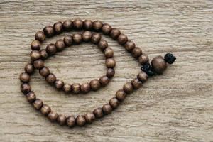 Brown wooden prayer rosary on a wooden background