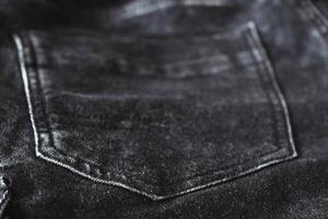 Fragment of black denim trousers with a back pocket photo