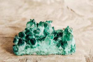 Raw emerald and gemstone rough rock crystal on a wooden table. Copy, empty space for text