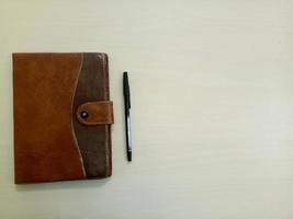 un viejo cuaderno con bolígrafo. cuaderno sobre fondo blanco de madera con área de espacio de copia foto