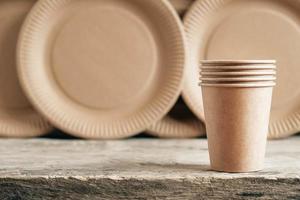 Paper cups with plates on wooden background photo