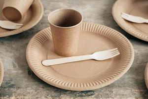 Wooden forks and paper cups with plates on wooden background photo