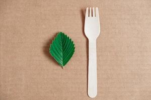 Wooden fork on a cardboard background. Eco friendly disposable tableware. Top view. Copy, empty space for text photo