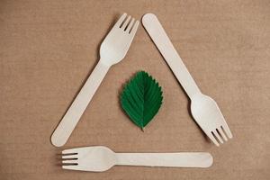 Wooden forks on a cardboard background. Eco friendly disposable tableware. Top view. Copy, empty space for text photo