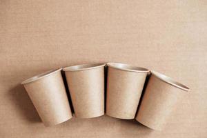 Disposable paper cups on kraft paper background. Eco friendly disposable tableware. Zero waste concept. Top view. Copy, empty space for text photo