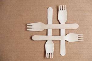 Wooden forks on a cardboard background. Eco friendly disposable tableware. Top view. Copy, empty space for text photo