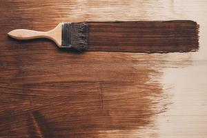 Brush with wooden handle and natural bristles against background of painted brown wooden planks photo