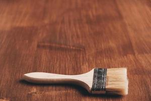 Brush with wooden handle and natural bristles against background of painted brown wooden planks photo