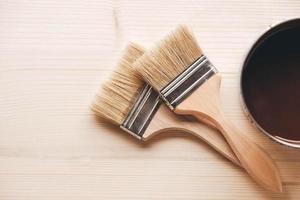 Paint brushes on a jar with brown paint on a wooden background photo