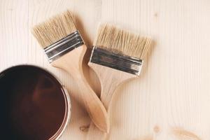 Paint brushes on a jar with brown paint on a wooden background