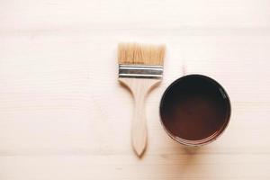 Paint brush on a jar with brown paint on a wooden background photo