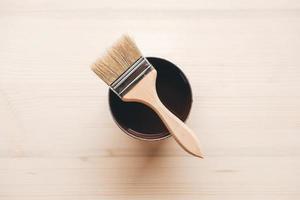 Paint brush on a jar with brown paint on a wooden background photo