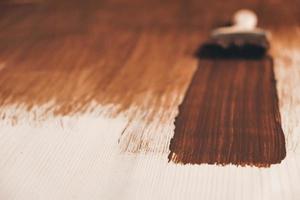 Brush with wooden handle and natural bristles against background of painted brown wooden planks photo