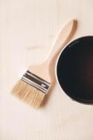 Paint brush on a jar with brown paint on a wooden background photo