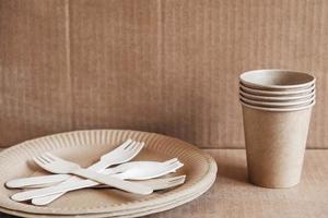 Wooden forks and paper cups with plates on kraft paper background photo