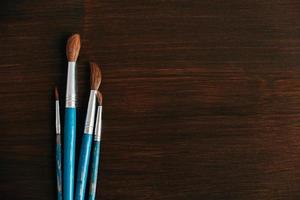 Group of artistic brushes for watercolor paints on a wooden background photo