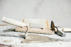 Old construction tools for plaster on vintage wood bench. Trowels and other masonry tools. Copy, empty space for text photo