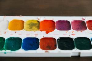 Set of watercolor paints on a dark wooden background photo