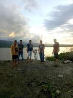 indonesia, julio de 2021 -un grupo de jóvenes disfrutando de la puesta de sol desde el borde del lago foto