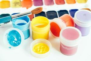 Colorful gouache paints and brush for painting on white wooden table. Top view. Copy, empty space for text photo
