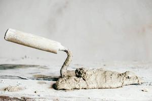 Old used metal masonry trowel on vintage small wood bench. Trowels and other masonry tools. Copy, empty space for text photo