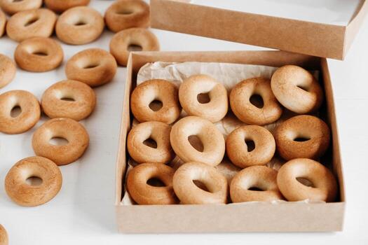 Drying or round bagels in a paper box on a white wooden background. Top view. Copy, empty space for text photo