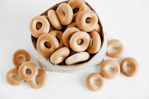 Drying or round bagels in a paper bag on a white wooden background. Top view. Copy, empty space for text photo