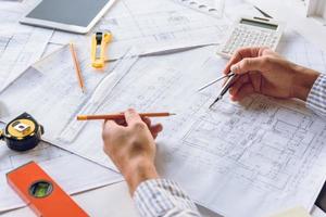 partial view of architect working with blueprints on new building design