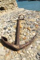 Old anchor lies on stones. Sunny day photo