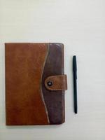 un viejo cuaderno con bolígrafo. cuaderno sobre fondo blanco de madera con área de espacio de copia foto