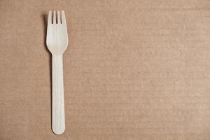 Wooden fork on a cardboard background. Eco friendly disposable tableware. Top view. Copy, empty space for text photo