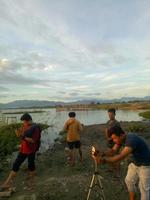 indonesia, julio de 2021 -un grupo de jóvenes disfrutando de la puesta de sol desde el borde del lago foto